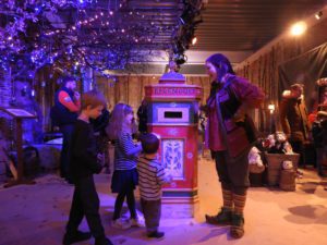 Children and elf posting letters in post box in LaplandUK Wishing Store