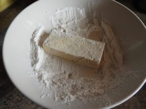 sliced tofu being dipped in flour coating