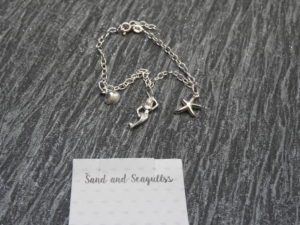 Charm bracelet with close up of Sand and Seagulls logo